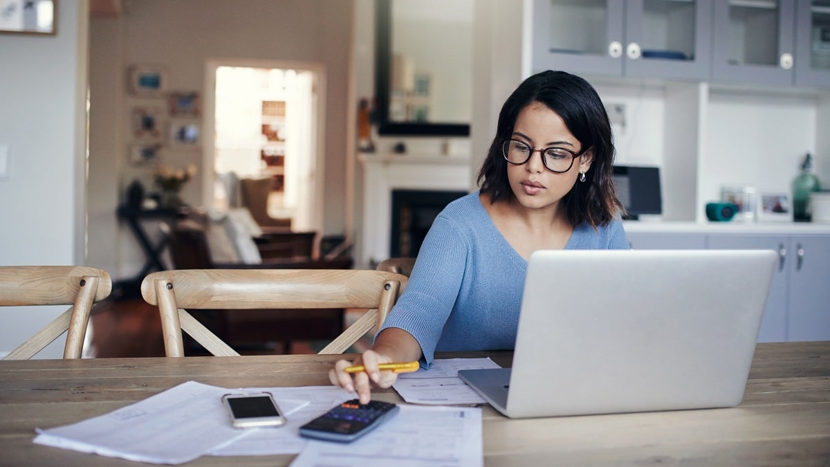 woman using calculator and laptop to do taxes