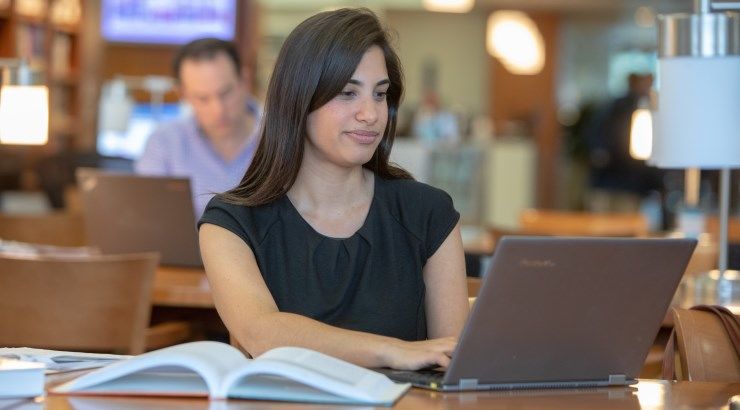 student typing on laptop in library