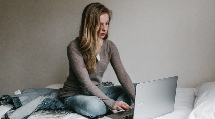 girl typing on laptop on bed