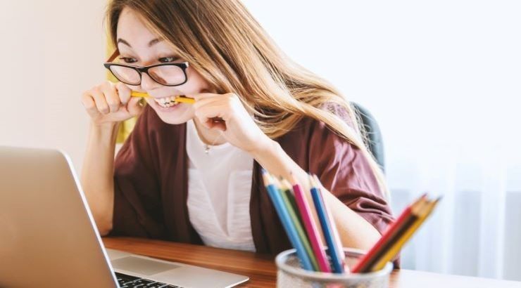 woman biting pencil at desk