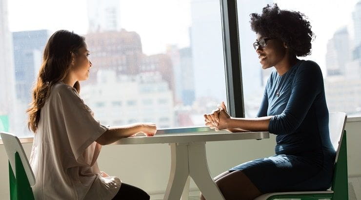 two women talking a table