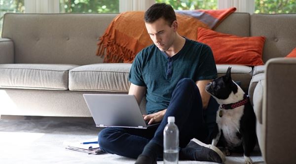 man on laptop next to dog