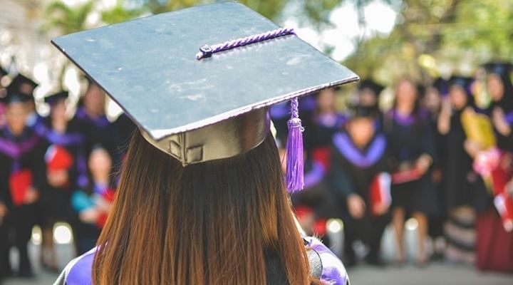 female graduate looking out at group of grads