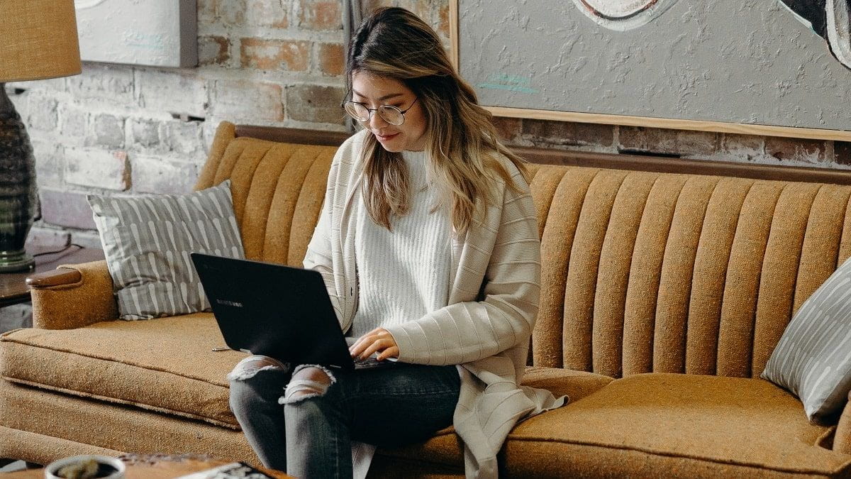 woman sitting on couch using laptop