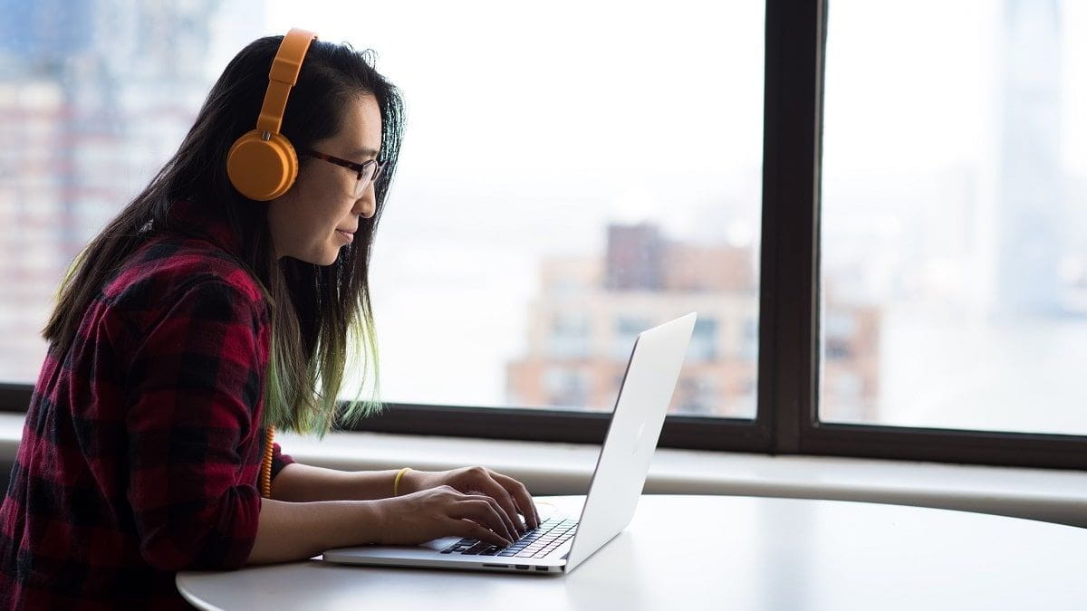 woman wearing headphones working on laptop
