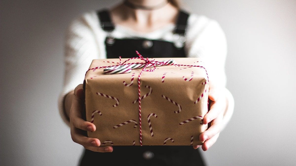 person holding out gift in candy cane wrapping paper