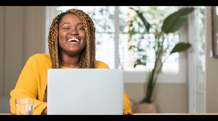female laughing and typing on laptop